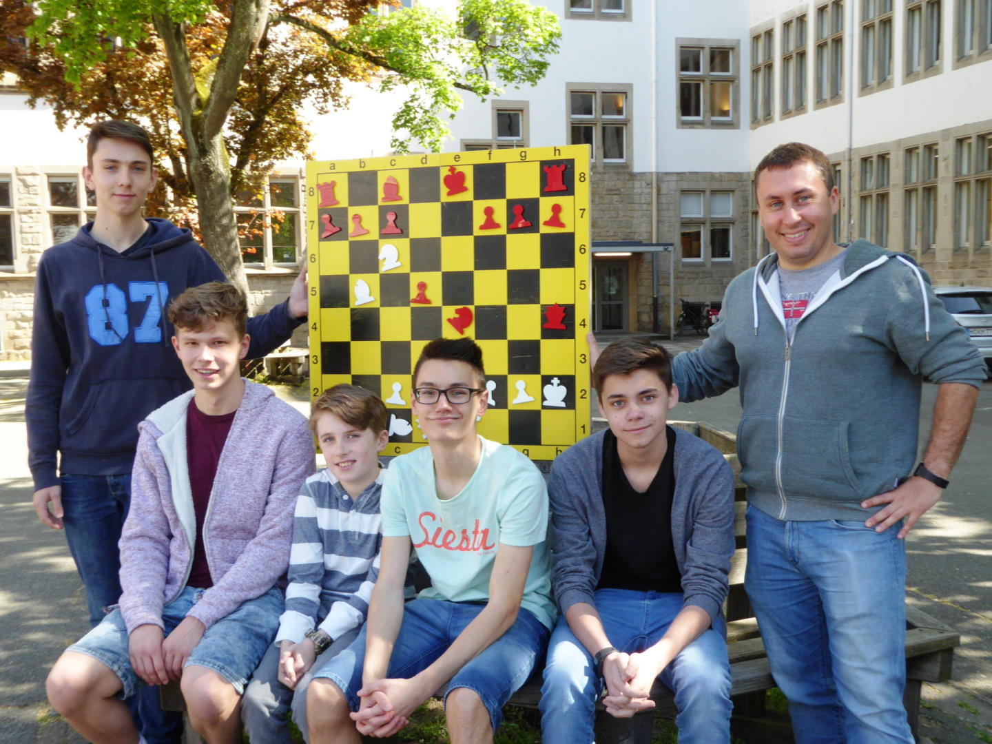 die Schüler und Schülerinnen der Schach AG posieren vor einem großen Schachbrett